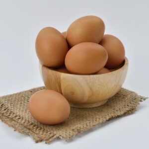 High resolution image of brown eggs in a wooden bowl placed on burlap fabric, ideal for food-themed content.