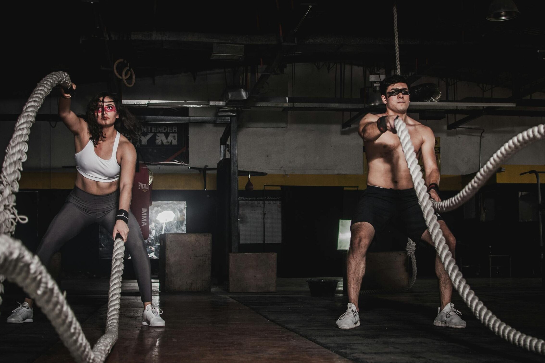 Two people engage in a powerful indoor battle rope workout, showcasing strength and energy.